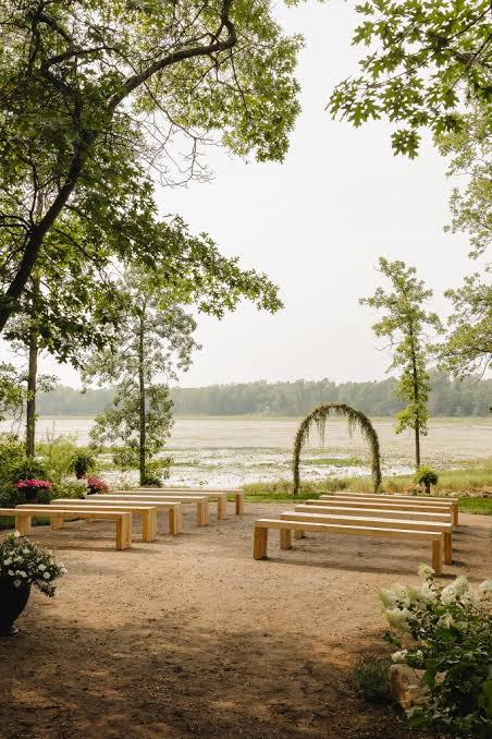 Wooden benches and a floral arch facing the lake for a ceremony